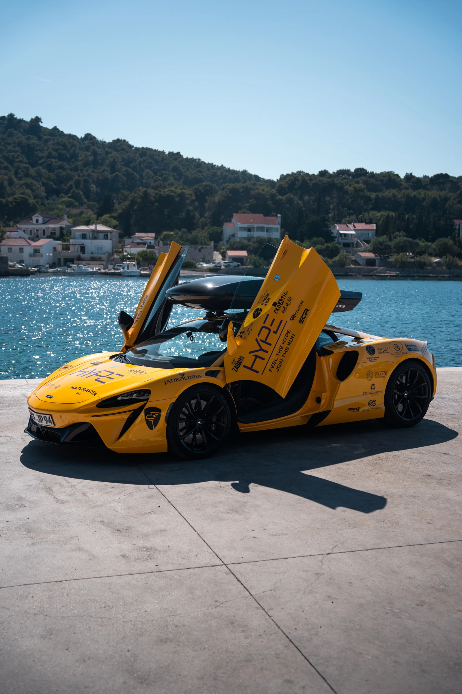 Mein gelber McLaren Artura mit geöffneten Türen vor der Küste