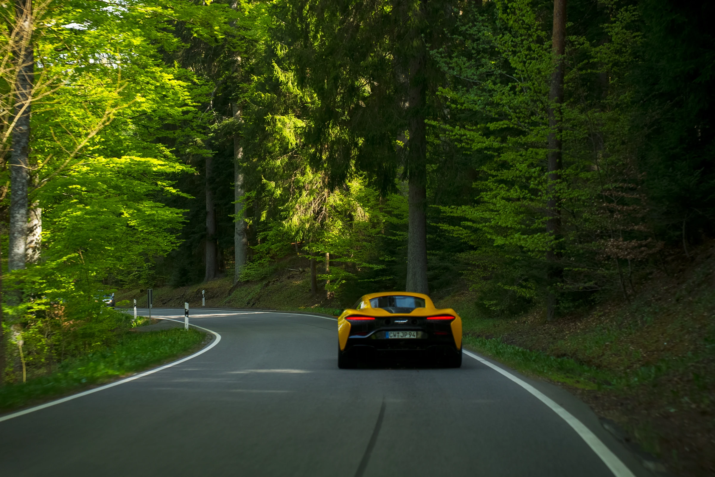 Mein gelber McLaren Artura auf einer kurvigen Straße im grünen Schwarzwald